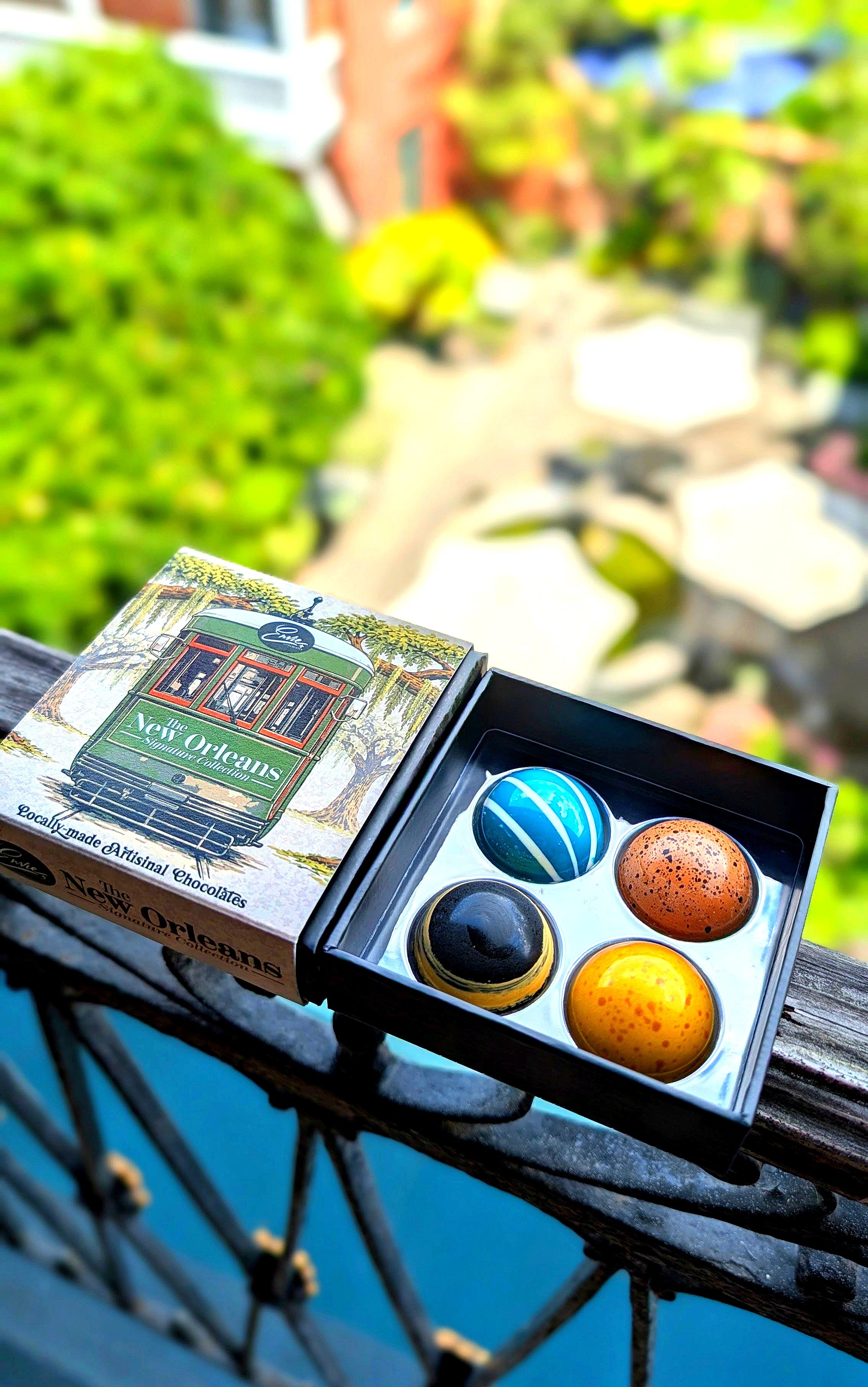 New Orleans Signature Collection open box on French Quarter balcony showing all four chocolates