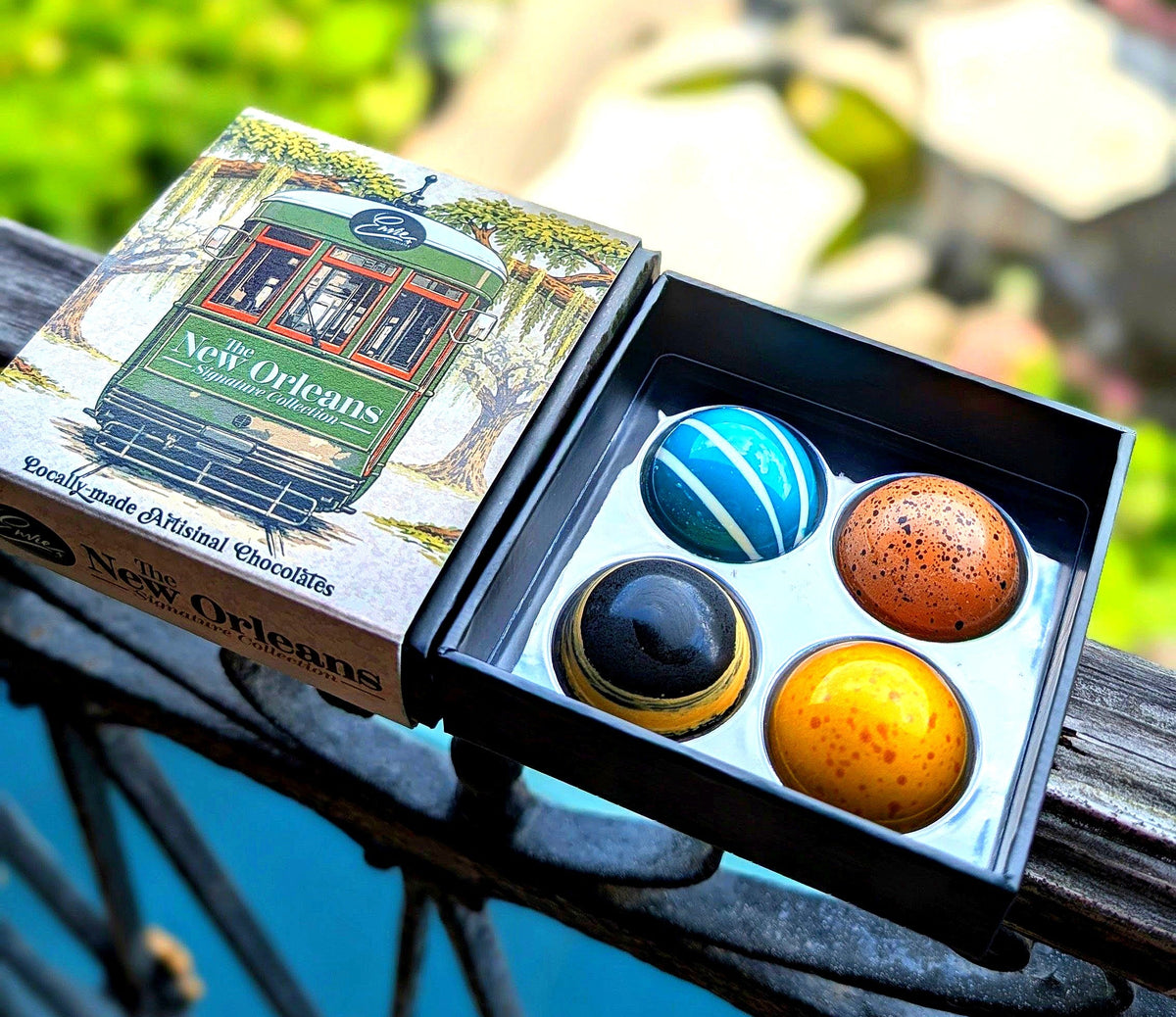 New Orleans Signature Collection open box on French Quarter balcony showing all four chocolates